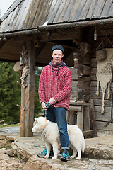 Image showing young hipster with dog in front of wooden house