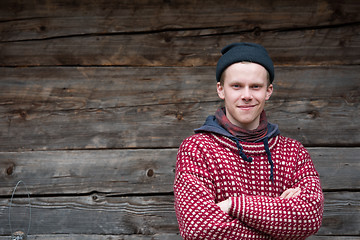 Image showing young hipster in front of wooden house