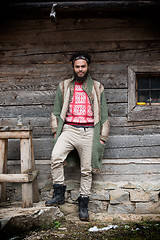 Image showing portrait of young hipster in front of wooden house