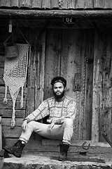 Image showing portrait of young hipster in front of wooden house