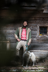 Image showing hipster with dog in front of wooden house