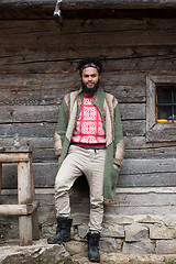 Image showing portrait of young hipster in front of wooden house