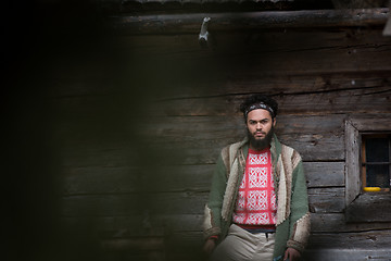 Image showing portrait of young hipster in front of wooden house