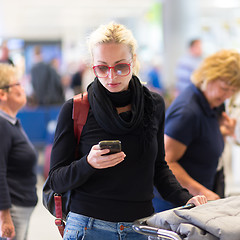 Image showing Female traveler using cell phone while waiting.