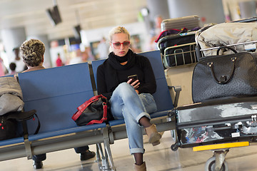 Image showing Female traveler using cell phone while waiting.