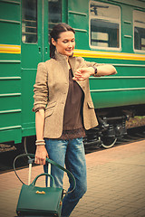 Image showing beautiful woman looks at his watch on the platform of the railwa