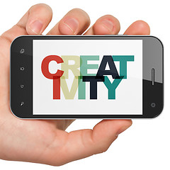 Image showing Marketing concept: Hand Holding Smartphone with Creativity on  display