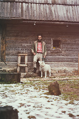 Image showing hipster with dog in front of wooden house