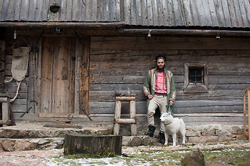 Image showing hipster with dog in front of wooden house