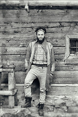 Image showing portrait of young hipster in front of wooden house