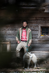 Image showing hipster with dog in front of wooden house