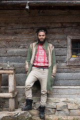 Image showing portrait of young hipster in front of wooden house