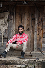 Image showing portrait of young hipster in front of wooden house