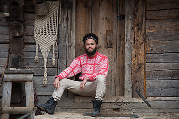 Image showing portrait of young hipster in front of wooden house