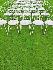 Image showing Green lawn with empty white chairs