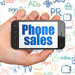 Image showing Advertising concept: Hand Holding Smartphone with Phone Sales on display