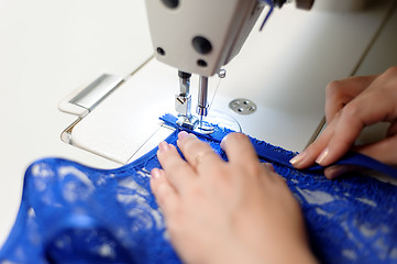 Image showing Hands of a woman sewing blue fabric