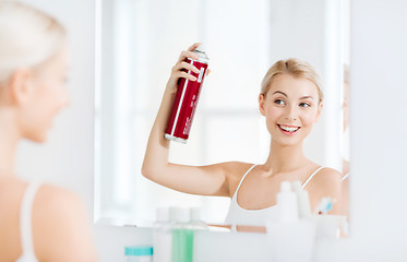 Image showing woman with hairspray styling her hair at bathroom