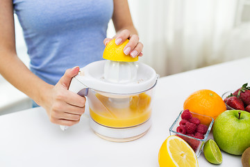 Image showing close up of woman squeezing fruit juice at home