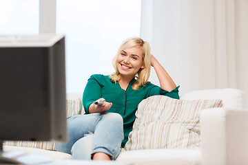 Image showing smiling woman with remote watching tv at home