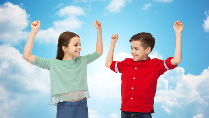 Image showing happy boy and girl celebrating victory over sky