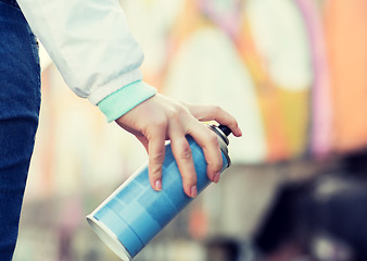 Image showing close up of hand holding spray paint and graffiti