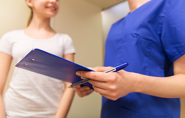 Image showing close up of nurse with clipboard and pen with girl