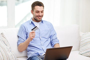 Image showing smiling man with laptop and credit card at home