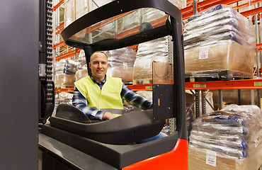 Image showing smiling man operating forklift loader at warehouse