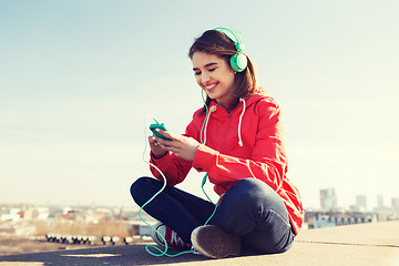 Image showing happy young woman with smartphone and headphones