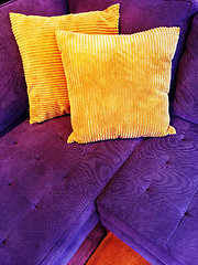 Image showing Vibrant purple sofa with orange cushions