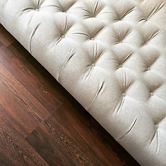 Image showing Fancy white ottoman on dark wooden floor