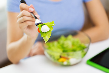 Image showing close up of young woman eating salad at home