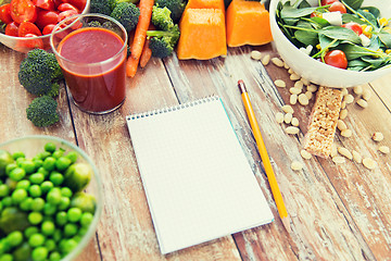 Image showing close up of ripe vegetables and notebook on table