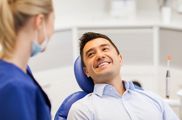 Image showing female dentist with happy male patient at clinic