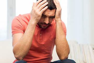 Image showing unhappy man suffering from head ache at home