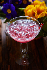 Image showing cosmopolitan cocktail garnished with ice on wooden table 