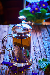 Image showing Flower tea in glass pot on a wooden table. 