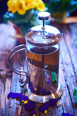 Image showing Flower tea in glass pot on a wooden table. 