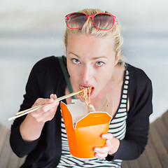 Image showing Woman eating Chinese take-away noodels.