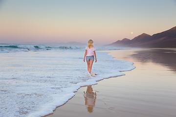 Image showing Lady walking on sandy beach in sunset.