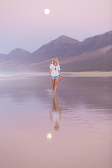 Image showing Lady walking on sandy beach in sunset.