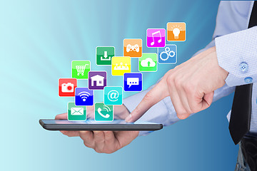 Image showing Businessman holding a tablet pc with mobile applications icons on virtual screen . Internet and business concept.