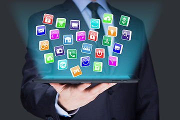 Image showing Businessman holding a tablet pc with mobile applications icons on virtual screen . Internet and business concept.