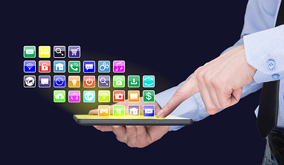 Image showing Businessman holding a tablet pc with mobile applications icons on virtual screen . Internet and business concept.