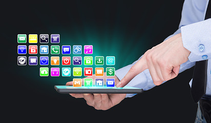 Image showing Businessman holding a tablet pc with mobile applications icons on virtual screen . Internet and business concept.