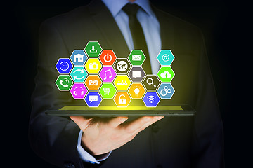 Image showing Businessman holding a tablet pc with mobile applications icons on virtual screen . Internet and business concept.