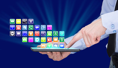 Image showing Businessman holding a tablet pc with mobile applications icons on virtual screen . Internet and business concept.