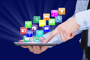 Image showing Businessman holding a tablet pc with mobile applications icons on virtual screen . Internet and business concept.