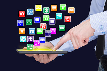 Image showing Businessman holding a tablet pc with mobile applications icons on virtual screen . Internet and business concept.